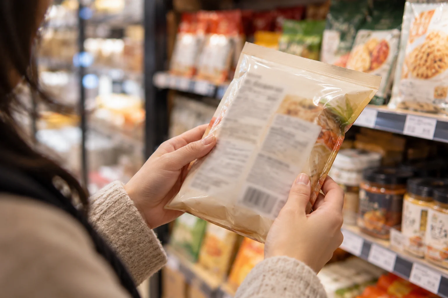 Hands checking a packaged food label.