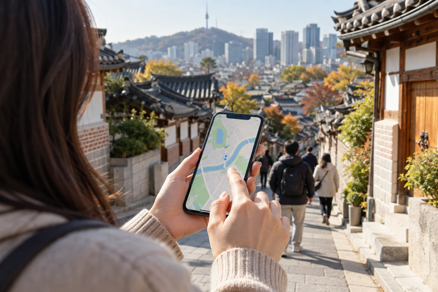 Hands looking at an abstract phone map near a Seoul street, no readable addresses